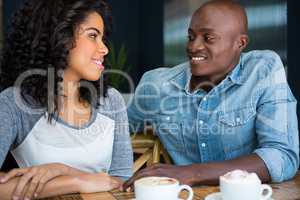 Couple looking at each other at table in coffee shop
