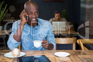 Man talking on phone while having coffee in coffee shop