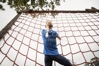 Woman climbing a net during obstacle course