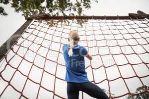 Woman climbing a net during obstacle course