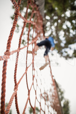 Woman climbing a net during obstacle course