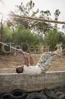 Young military soldier practicing rope climbing during obstacle course