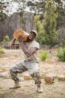 Military soldier carrying a tree log during obstacle course