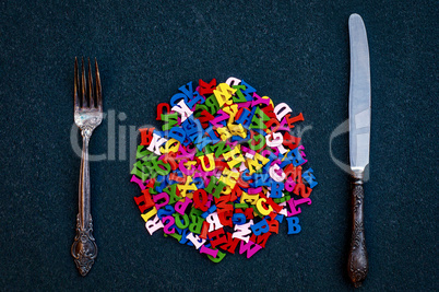 many wooden letters of the English alphabet among the fork and k