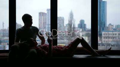 Silhouette of couple reading book on windowsill