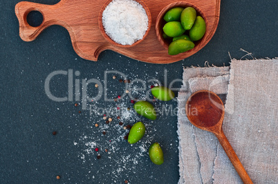 Large green olives and salt, wooden spoon