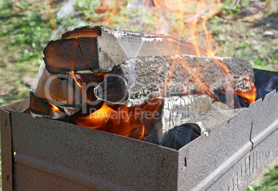 Firewood burns in rusty metal tray