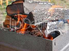 Firewood burning in metal tray close-up