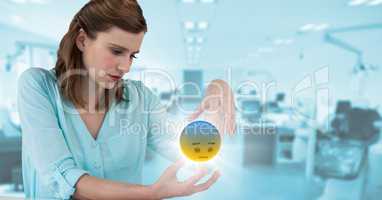 Woman sitting with emoji and flare between hands against blurry blue office