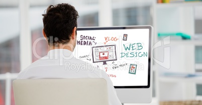 Rear view of businessman analyzing plan on computer