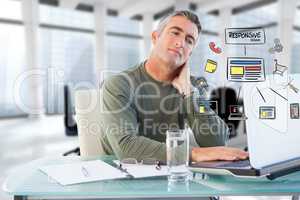 Digital composite image of businessman using laptop with icons at desk