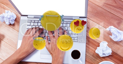 Hands using laptop by crumpled papers  while emojis flying around
