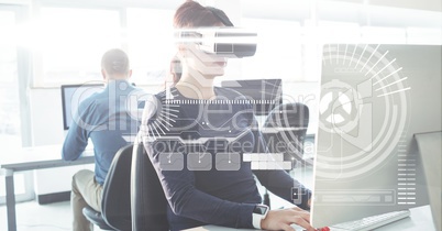 Businesswoman wearing VR glasses while using computer in office