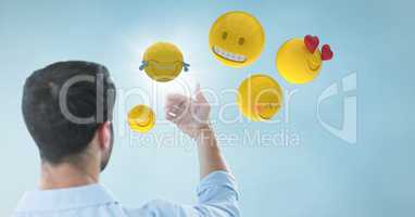 Back of man holding up glass device against blue background with emojis and flare