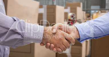 Close-up of business people shaking hands in warehouse