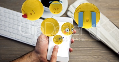 Hand using emojis on smart phone