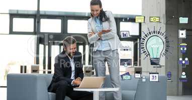 Business people using laptop by bulb sign in office