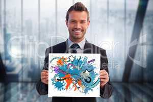 Portrait of smiling businessman holding colorful billboard in office