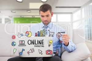 Businessman shopping online while sitting on sofa with online marketing text in foreground