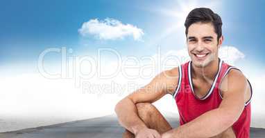 Male runner sitting on road against sky and sun