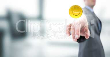 Business man pointing at emoji with flare against blurry grey office