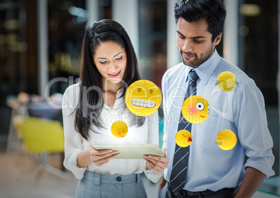 Business people with tablet and emojis with flares in blurry office