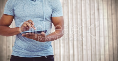 Man mid section with tablet against blurry wood panel