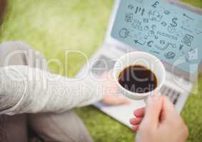 Woman on grass with coffee and laptop showing black business doodles and blue background