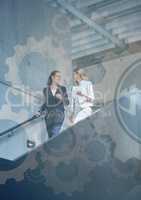 Business women wwalking down stairs with gear graphic overlay