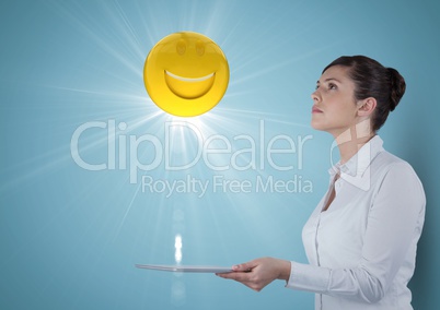 Business woman with tablet looking up at emoji and flare against blue background