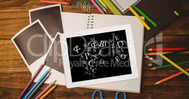 Overhead view of letters in digital tablet with photographs and color pencils on wooden table