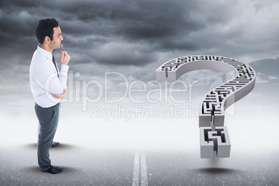 Digital composite image of businessman looking at maze question mark against sky