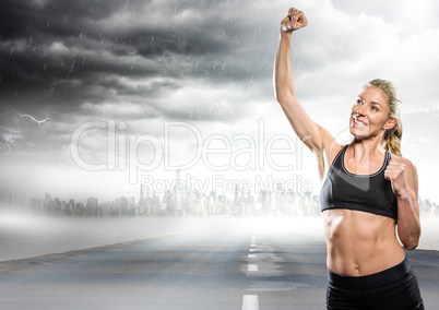 Female runner with hand in air on road and skyline with storm
