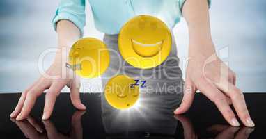 Close up of business woman's hands on table with emojis and flares against blurry blue wood panel