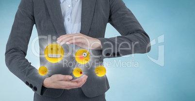 Mid section of business woman with emojis and flares between hands against blue background with clou