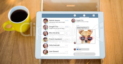 Digital tablet displaying social media website by coffee cup on table