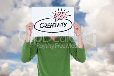 Man holding billboard with creativity text while standing against sky
