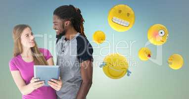 Man and woman with tablet and emojis against blue green background