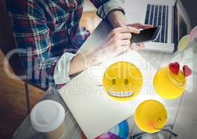 Man at desk with phone and emojis with flares