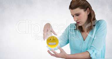 Woman sitting with emoji and flare between hands against white wall