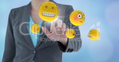 Business woman mid section touching emoji with flares against blue background