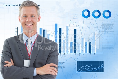 Happy businessman standing arms crossed against graphs