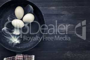 Raw eggs in a black frying pan