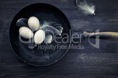 Three chicken eggs in the shell lie in a cast-iron frying pan