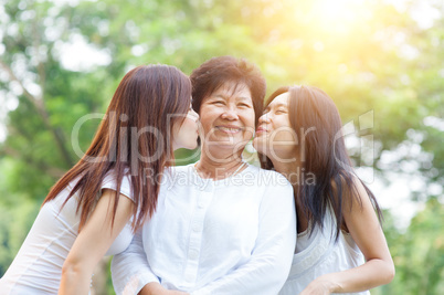 Daughters kissing elderly mother