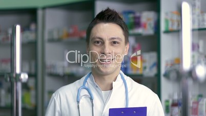 Smiling male pharmacist in white coat in drugstore