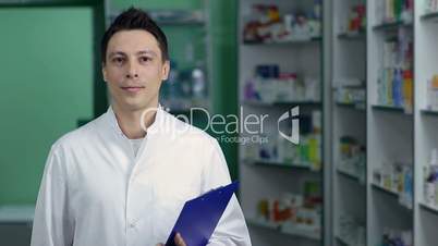Smiling male pharmacist in white coat at drugstore