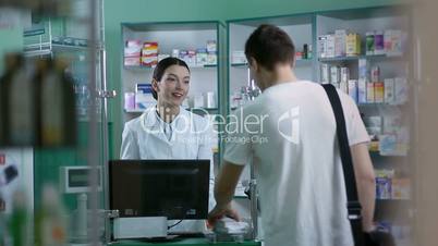 Smiling pharmacist giving client pills in pharmacy