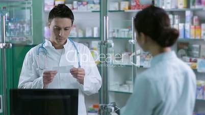Cheerful male pharmacist reading prescription