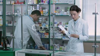 Chemist counting stock with colleague in pharmacy